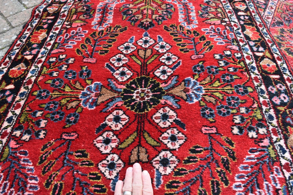 An exceptionally long hand-knotted Persian Sarouk runner rug featuring a deep red ground with detailed floral motifs and a multi-tiered dark border. View II