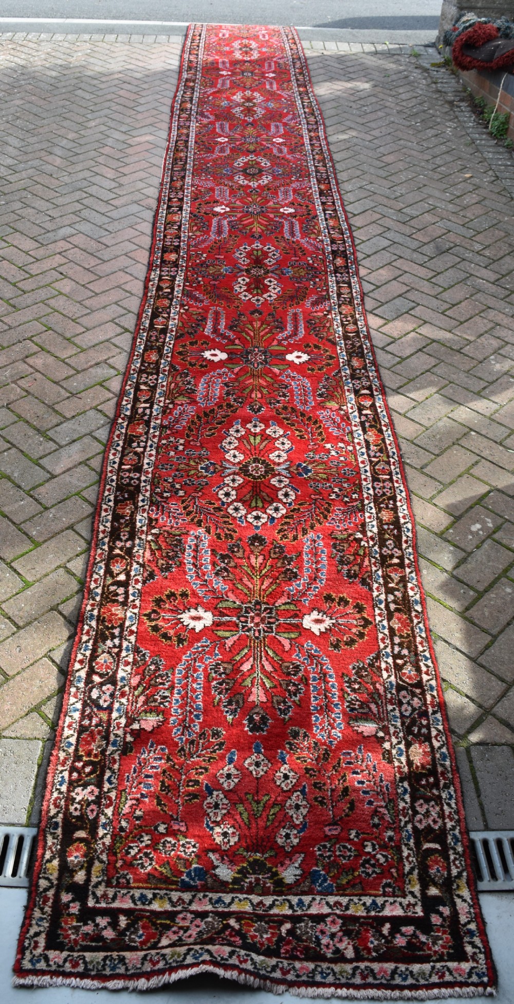 An exceptionally long hand-knotted Persian Sarouk runner rug featuring a deep red ground with detailed floral motifs and a multi-tiered dark border. View III