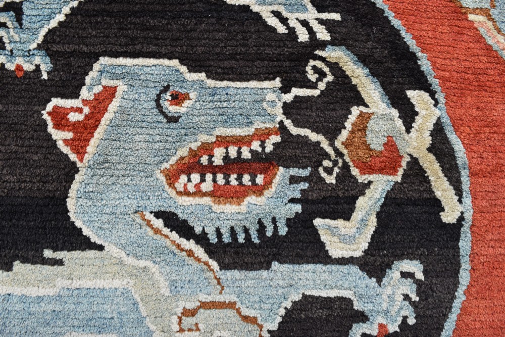 A square hand-knotted Tibetan wool rug featuring a central blue mythical beast inside a circular medallion on a red field with black geometric borders. View V