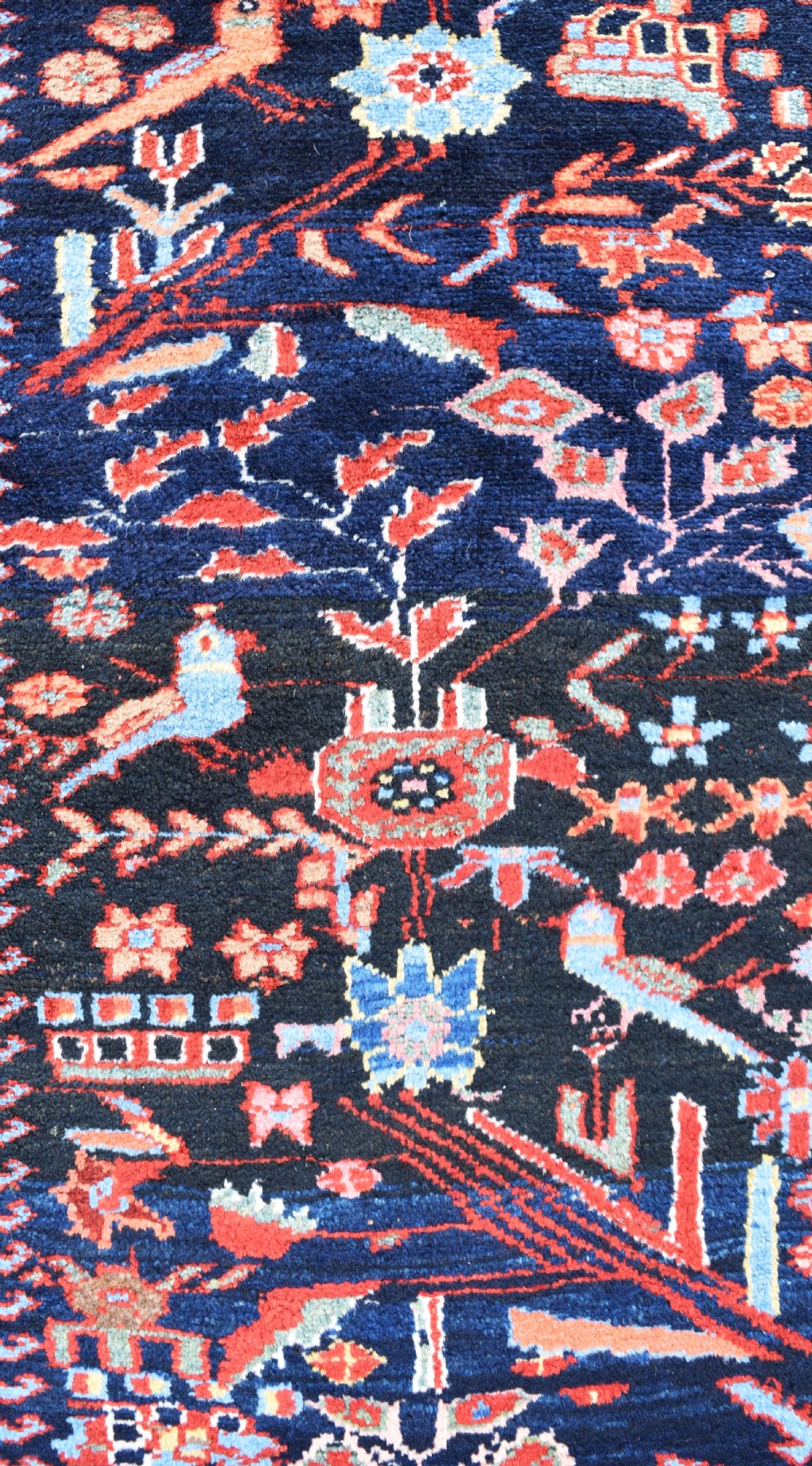 A long, narrow hand-knotted Bakhtiari wool runner rug featuring a navy blue field filled with stylised bird and botanical motifs, enclosed within a bright blue floral border. View V