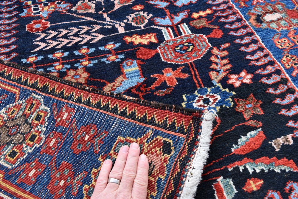 A long, narrow hand-knotted Bakhtiari wool runner rug featuring a navy blue field filled with stylised bird and botanical motifs, enclosed within a bright blue floral border. View VII