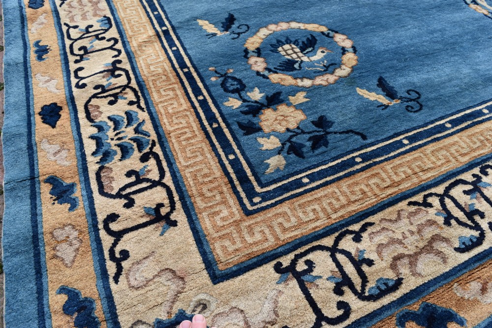 A rectangular hand-knotted wool carpet featuring a bright blue central field decorated with circular floral medallions and a broad beige geometric border. View II