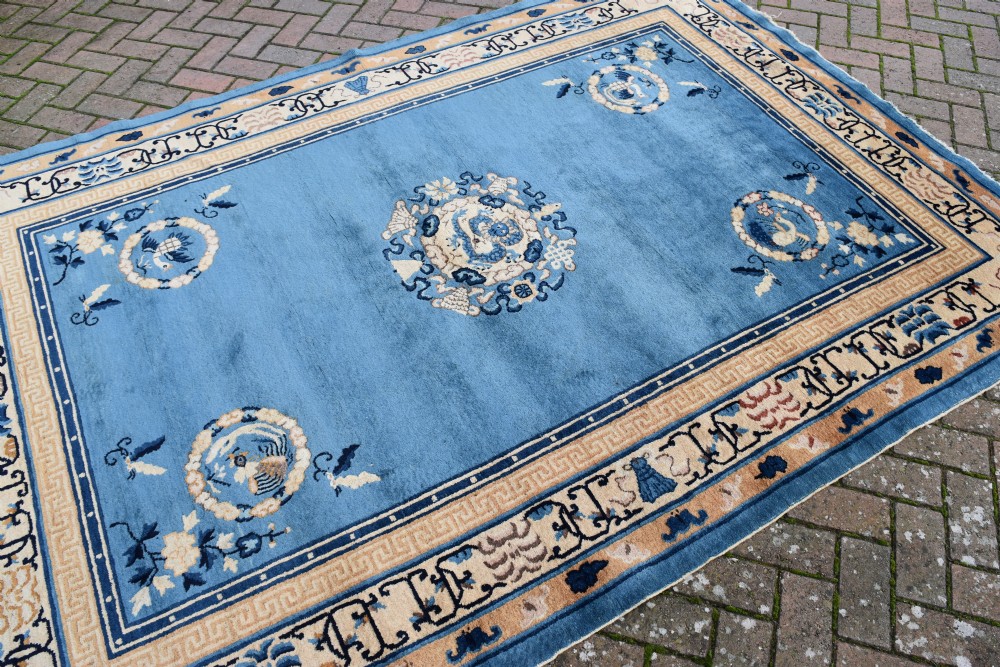 A rectangular hand-knotted wool carpet featuring a bright blue central field decorated with circular floral medallions and a broad beige geometric border. View IV