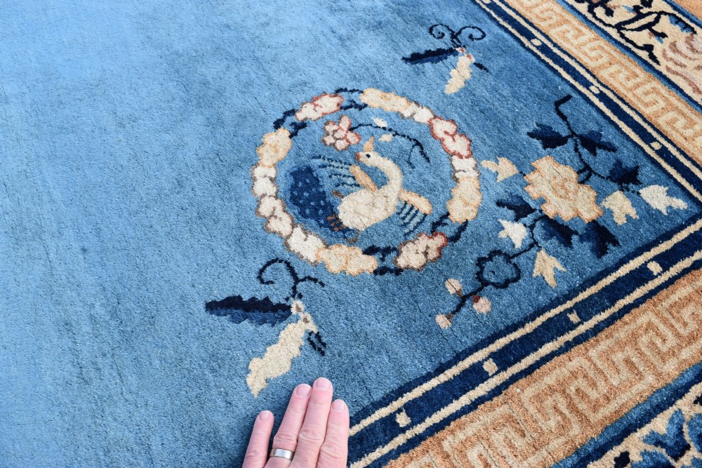 A rectangular hand-knotted wool carpet featuring a bright blue central field decorated with circular floral medallions and a broad beige geometric border. View V