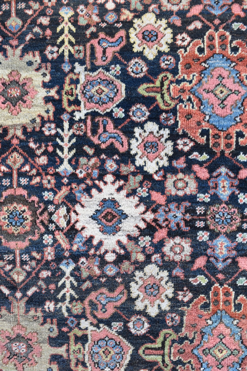 A large rectangular hand-knotted wool carpet featuring a dark navy central field filled with geometric floral motifs and framed by a wide terracotta border. View II