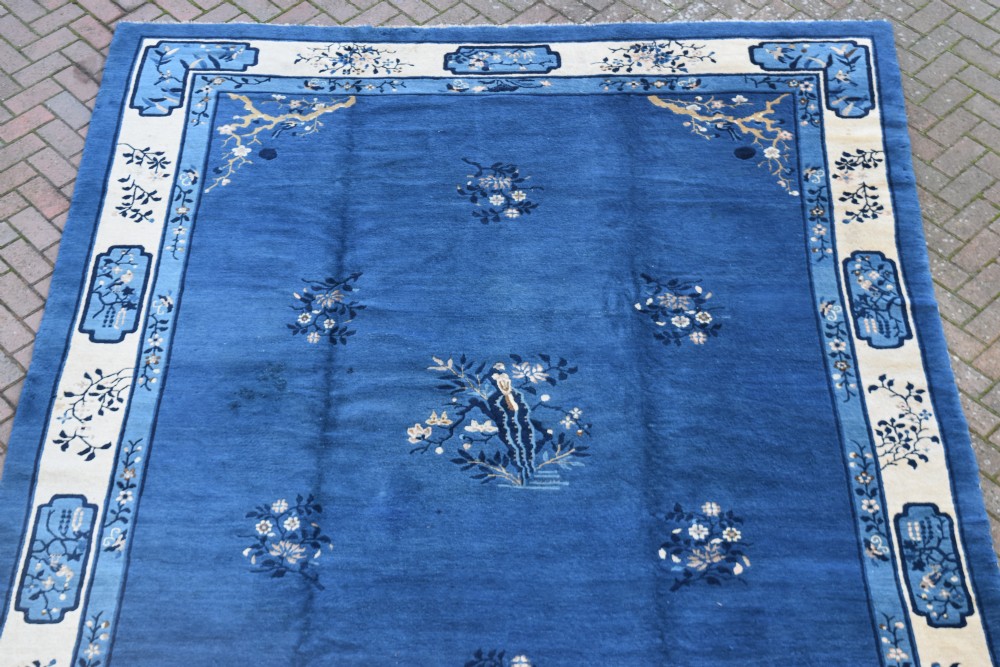 An antique blue and cream Chinese Peking carpet featuring floral motifs and a central bird design within decorative borders. View V