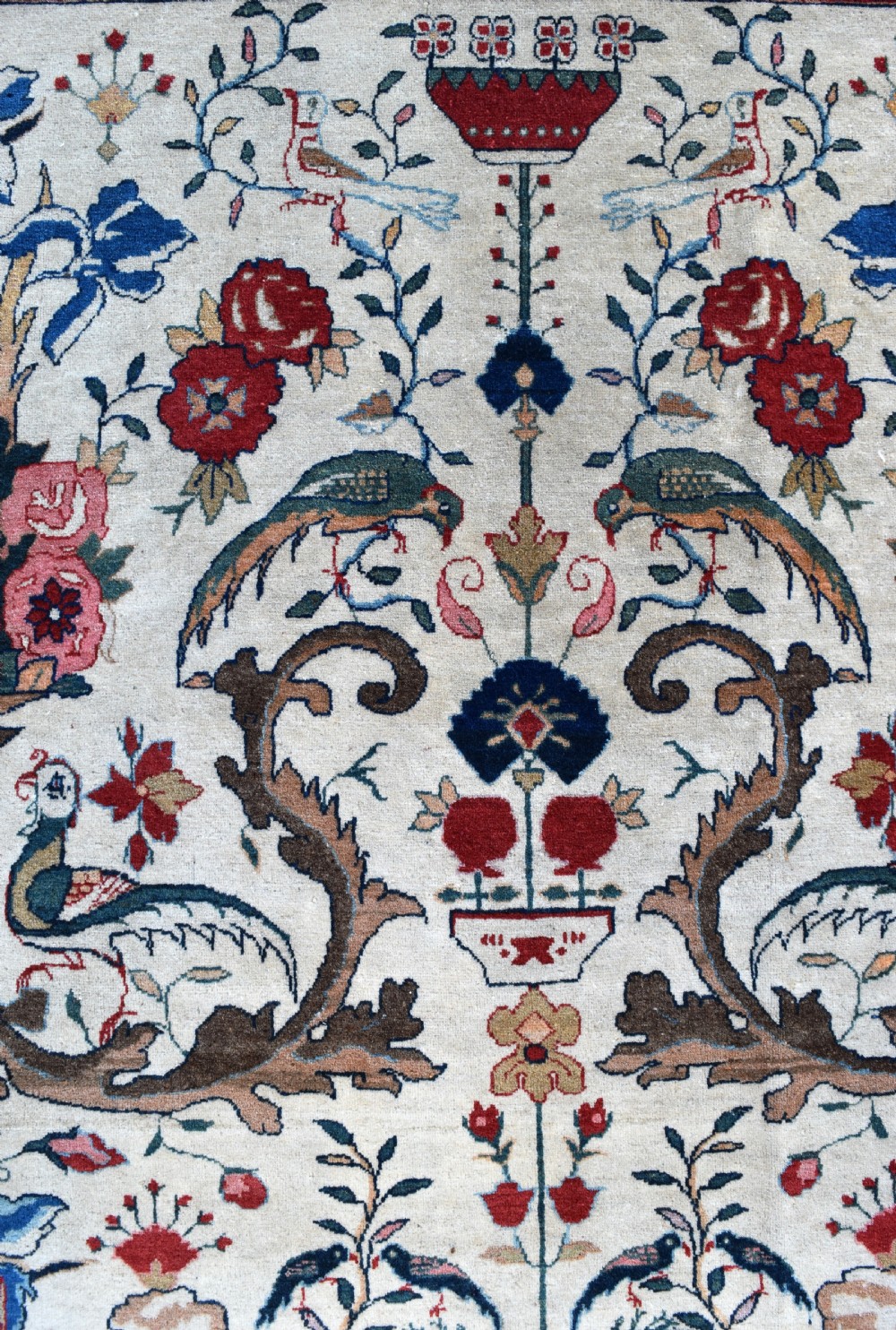 A large hand-knotted Persian Qum carpet featuring an ivory central field patterned with birds, urns, and floral motifs within a dark red border. View III