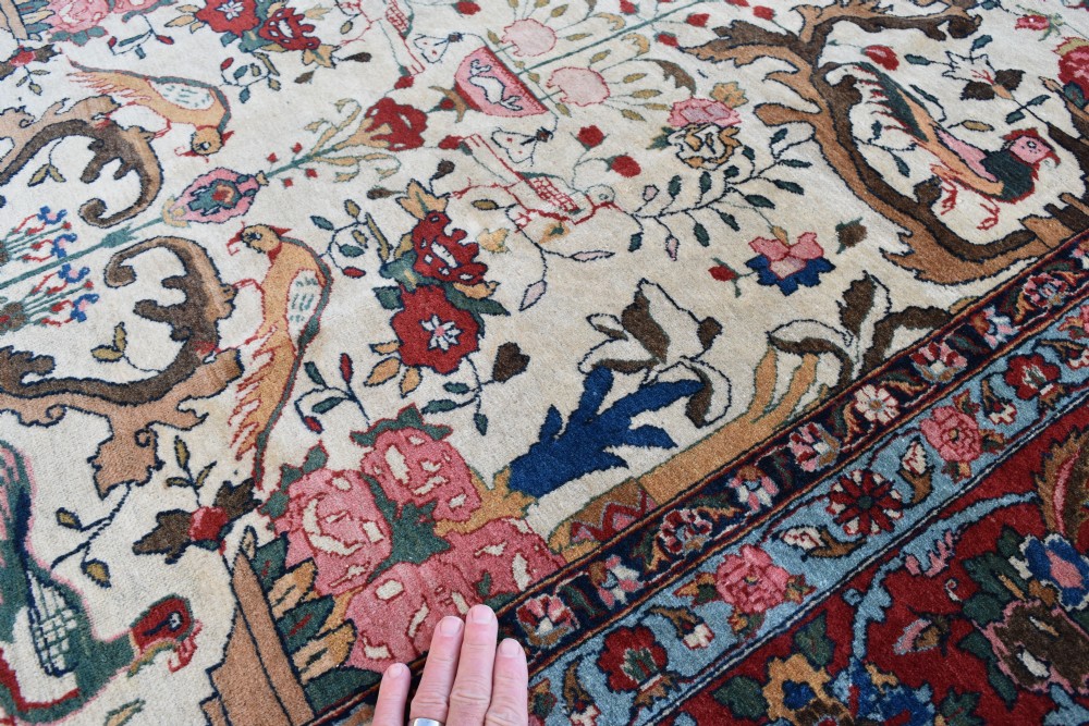 A large hand-knotted Persian Qum carpet featuring an ivory central field patterned with birds, urns, and floral motifs within a dark red border. View IV