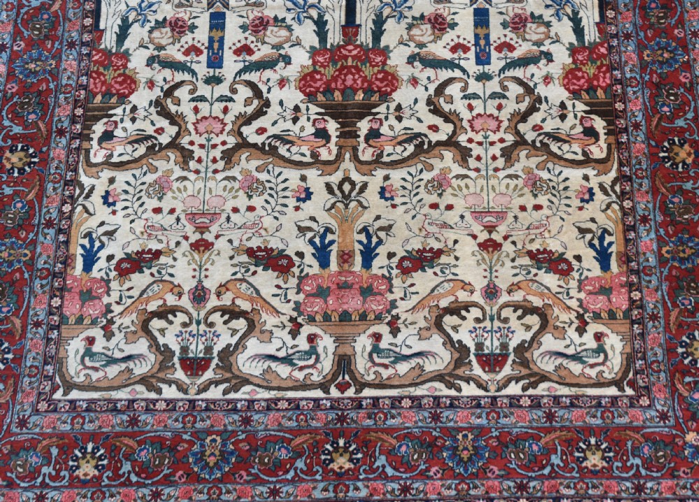 A large hand-knotted Persian Qum carpet featuring an ivory central field patterned with birds, urns, and floral motifs within a dark red border. View IX