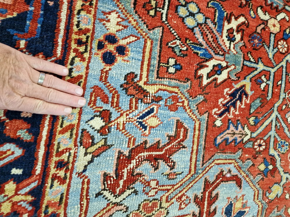 An antique hand-knotted Persian Heriz carpet with a central geometric navy medallion on a terracotta red field with light blue spandrels. View III