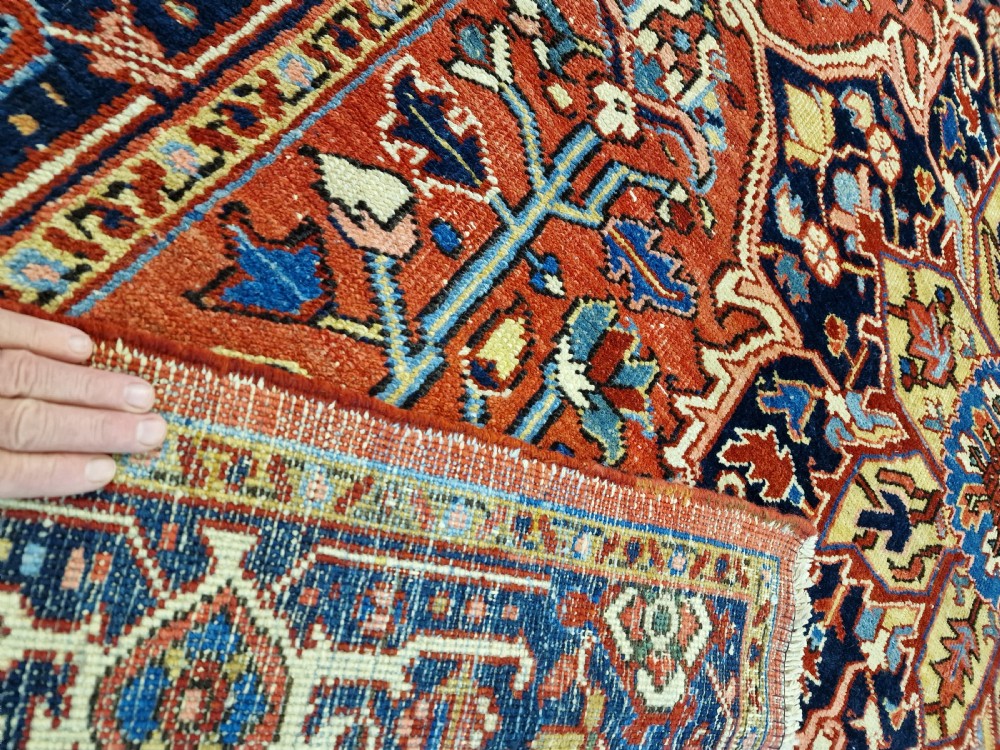 An antique hand-knotted Persian Heriz carpet with a central geometric navy medallion on a terracotta red field with light blue spandrels. View IV