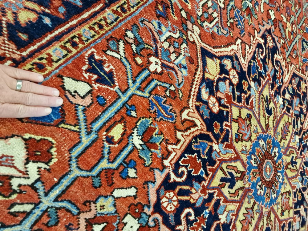 An antique hand-knotted Persian Heriz carpet with a central geometric navy medallion on a terracotta red field with light blue spandrels. View V