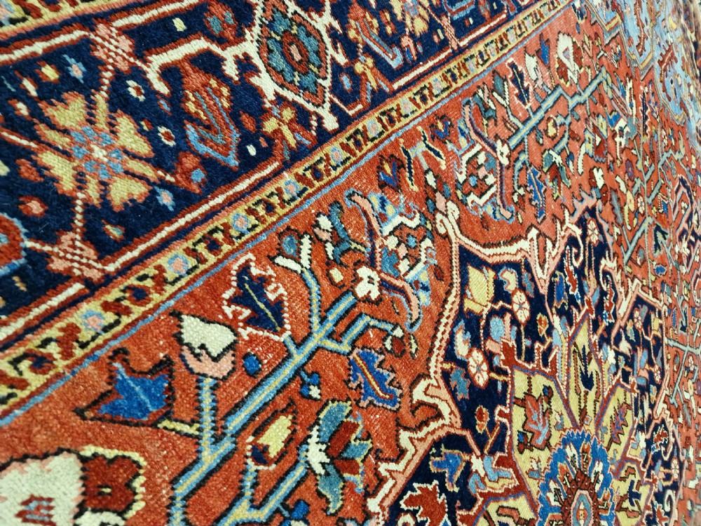 An antique hand-knotted Persian Heriz carpet with a central geometric navy medallion on a terracotta red field with light blue spandrels. View VI