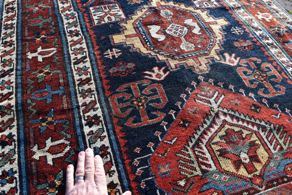 An antique Karadagh hand-knotted wool runner rug featuring geometric medallions on a navy blue central field framed by a wide terracotta red patterned border. View IV
