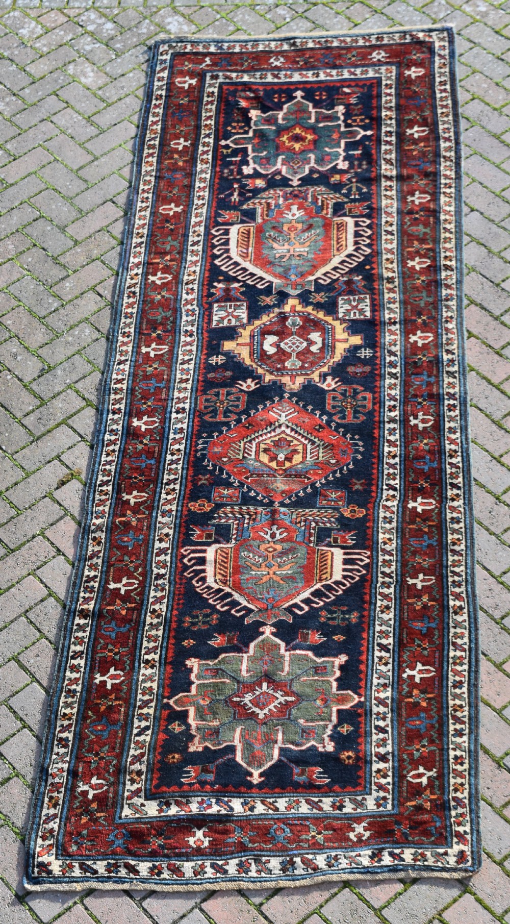 An antique Karadagh hand-knotted wool runner rug featuring geometric medallions on a navy blue central field framed by a wide terracotta red patterned border. View VI