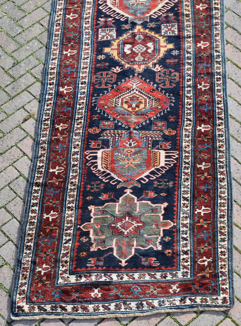 An antique Karadagh hand-knotted wool runner rug featuring geometric medallions on a navy blue central field framed by a wide terracotta red patterned border. View VII