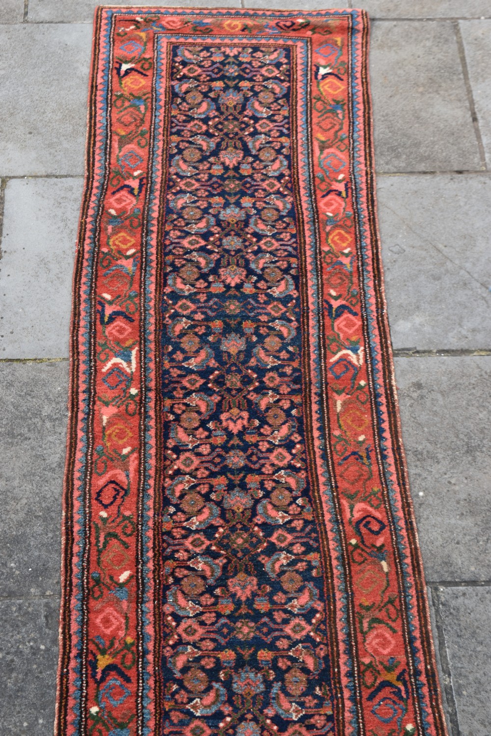 A long narrow hand-knotted antique Kurdish wool rug runner featuring a dark navy central field with repeating floral lattice patterns framed by a terracotta border. View III