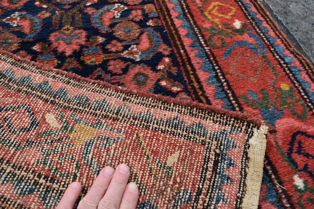 A long narrow hand-knotted antique Kurdish wool rug runner featuring a dark navy central field with repeating floral lattice patterns framed by a terracotta border. View IV