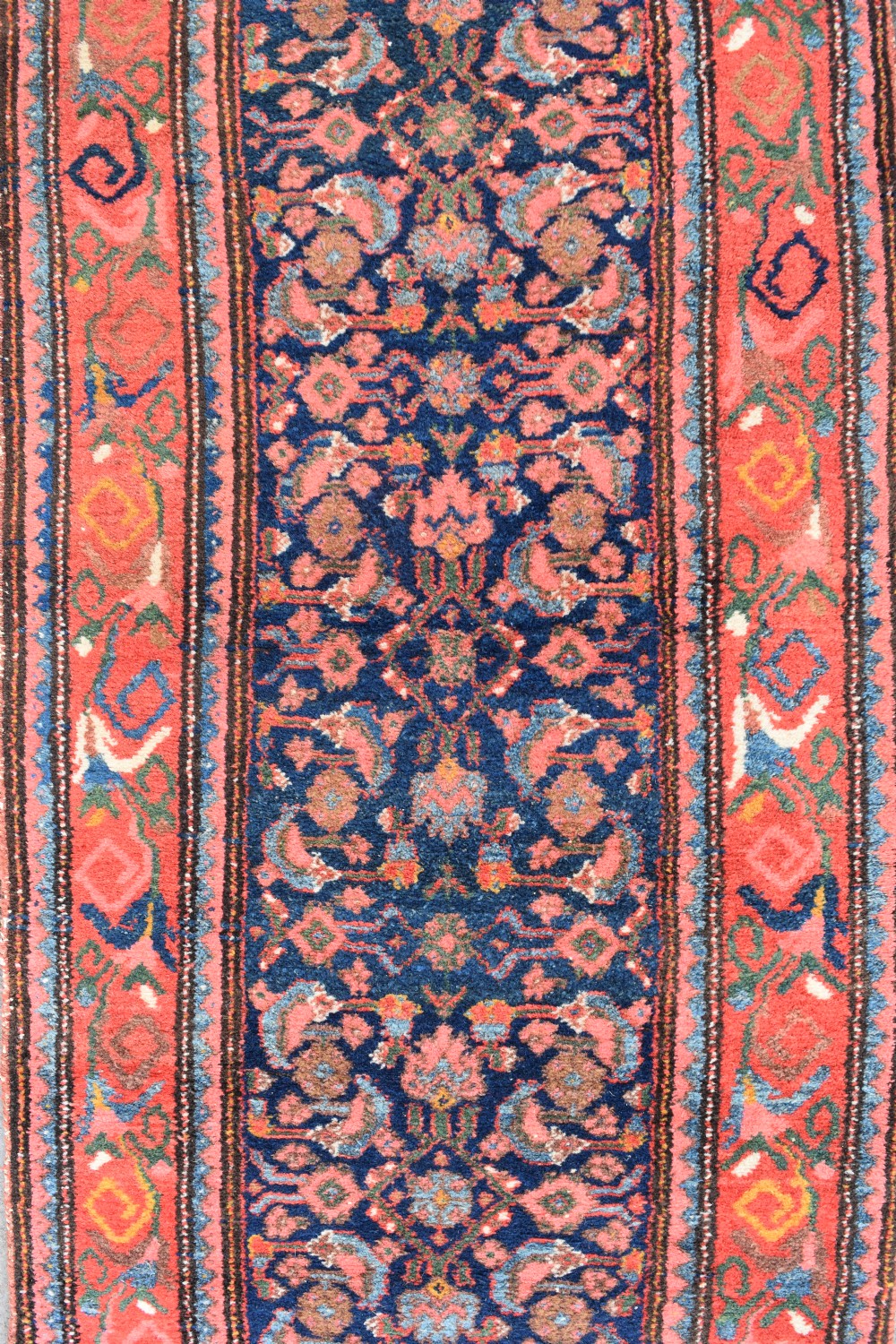 A long narrow hand-knotted antique Kurdish wool rug runner featuring a dark navy central field with repeating floral lattice patterns framed by a terracotta border. View V