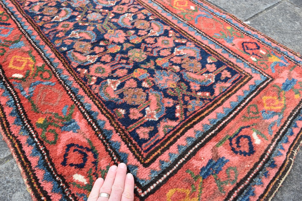 A long narrow hand-knotted antique Kurdish wool rug runner featuring a dark navy central field with repeating floral lattice patterns framed by a terracotta border. View VI
