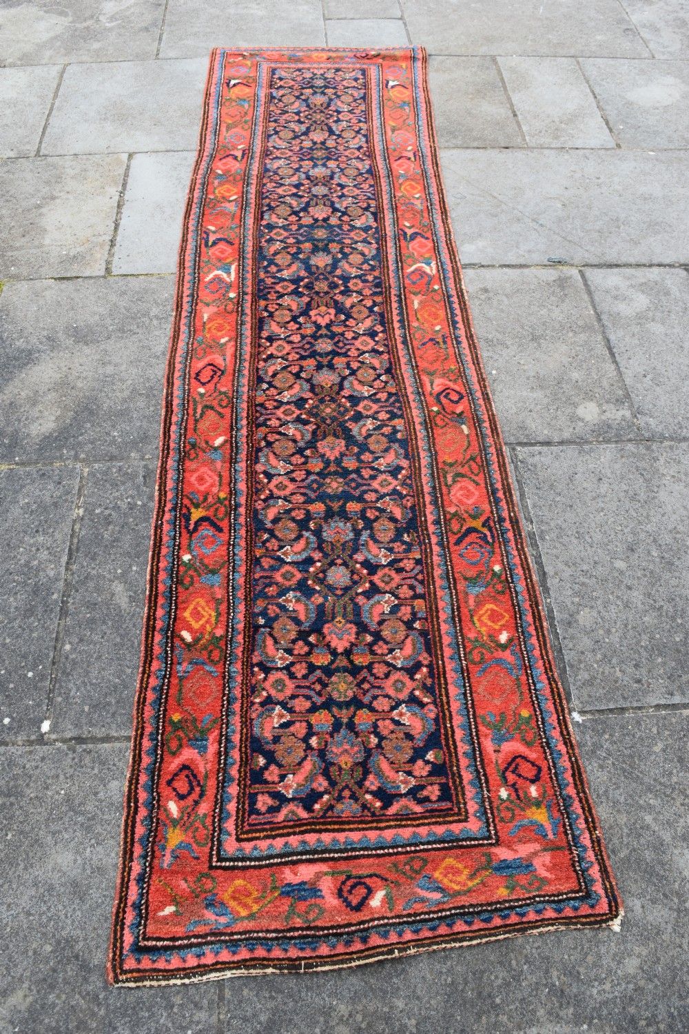 A long narrow hand-knotted antique Kurdish wool rug runner featuring a dark navy central field with repeating floral lattice patterns framed by a terracotta border. View VII