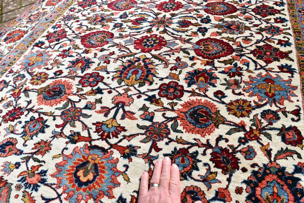 An antique hand-knotted Persian Qum rug featuring an ivory field filled with red and blue floral motifs, surrounded by a multi-band decorative border. View IV