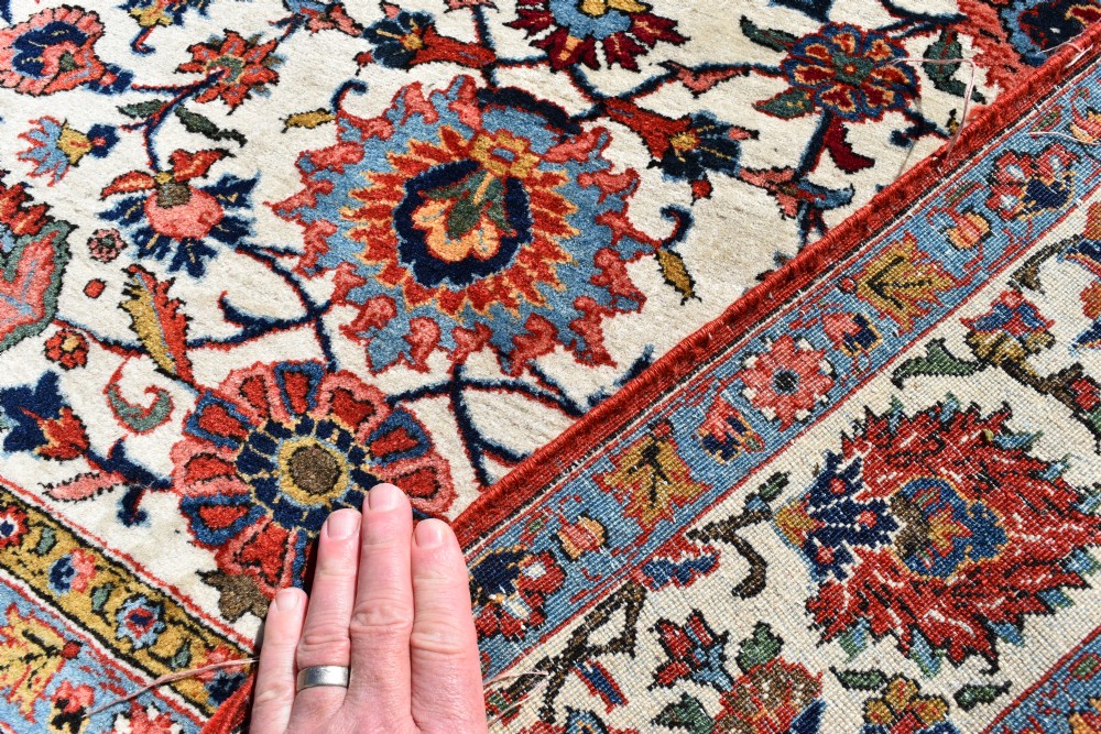 An antique hand-knotted Persian Qum rug featuring an ivory field filled with red and blue floral motifs, surrounded by a multi-band decorative border. View V