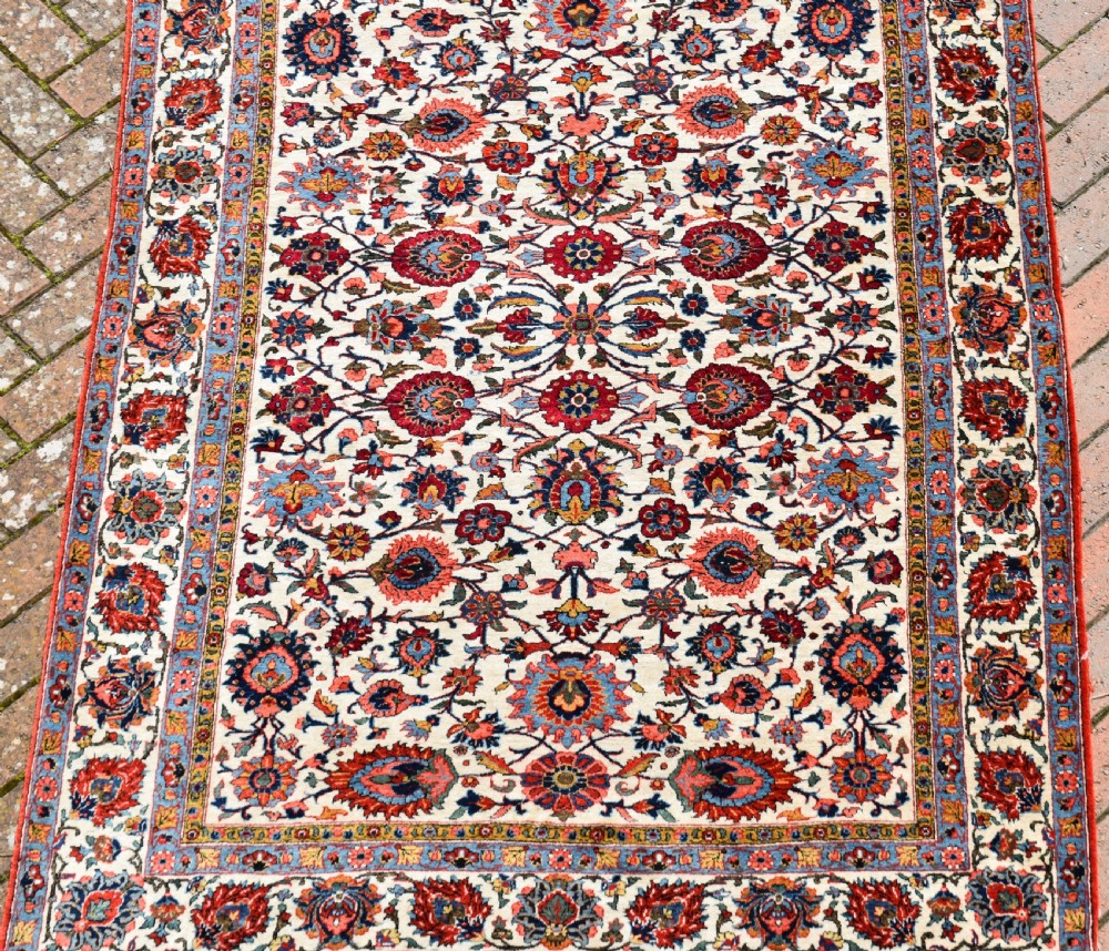 An antique hand-knotted Persian Qum rug featuring an ivory field filled with red and blue floral motifs, surrounded by a multi-band decorative border. View VII