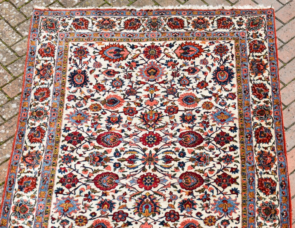 An antique hand-knotted Persian Qum rug featuring an ivory field filled with red and blue floral motifs, surrounded by a multi-band decorative border. View VIII