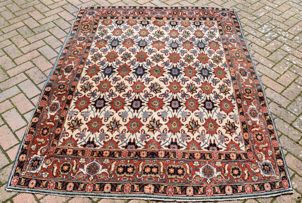 An antique hand-knotted Persian Veramin rug displaying a repeated Mina Khani floral pattern on a cream field framed by multiple dark red and blue decorative borders. View II