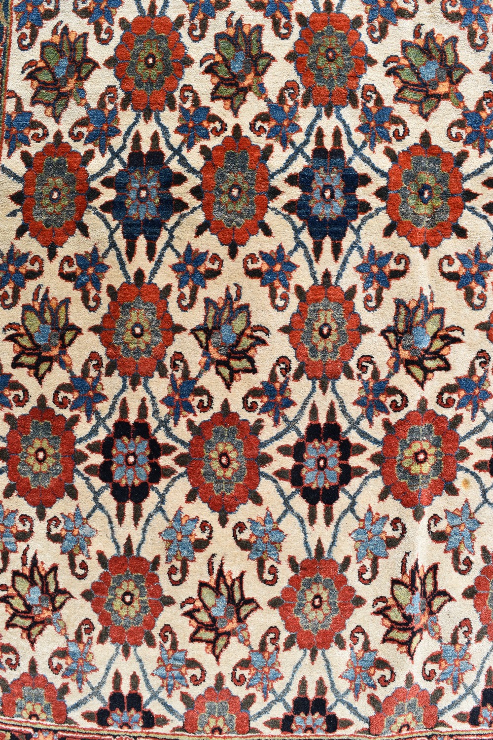 An antique hand-knotted Persian Veramin rug displaying a repeated Mina Khani floral pattern on a cream field framed by multiple dark red and blue decorative borders. View III