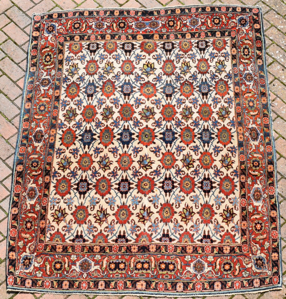An antique hand-knotted Persian Veramin rug displaying a repeated Mina Khani floral pattern on a cream field framed by multiple dark red and blue decorative borders. View VI