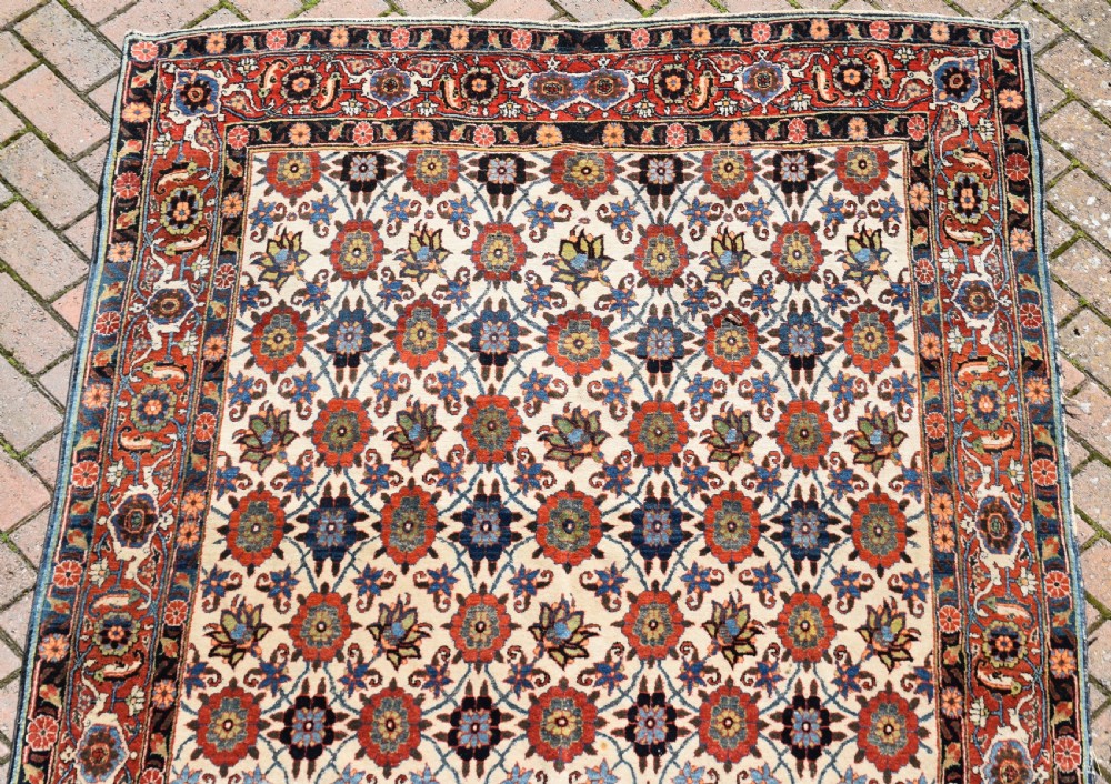 An antique hand-knotted Persian Veramin rug displaying a repeated Mina Khani floral pattern on a cream field framed by multiple dark red and blue decorative borders. View VIII