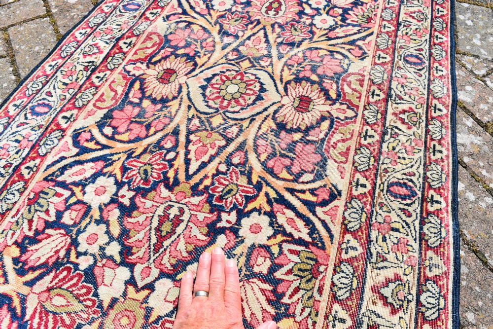 An exceptionally long and narrow hand-knotted antique Kirman rug runner featuring detailed floral medallion motifs in pink, navy blue, and cream. View IV