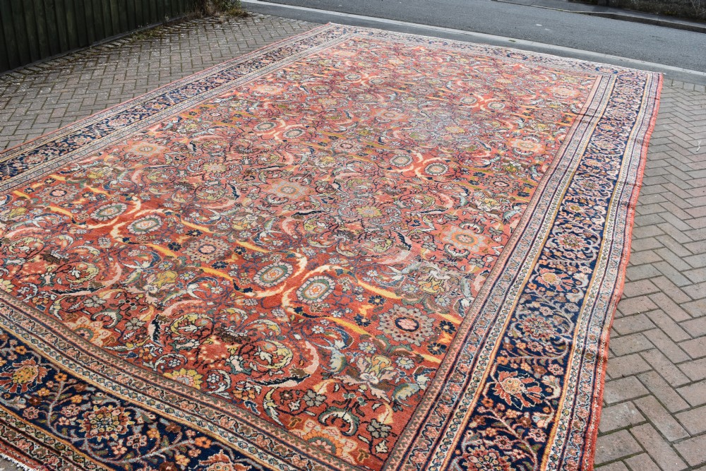 An oversized antique Persian Mahal wool carpet with a floral arabesque pattern on a terracotta field and a dark navy border. View III