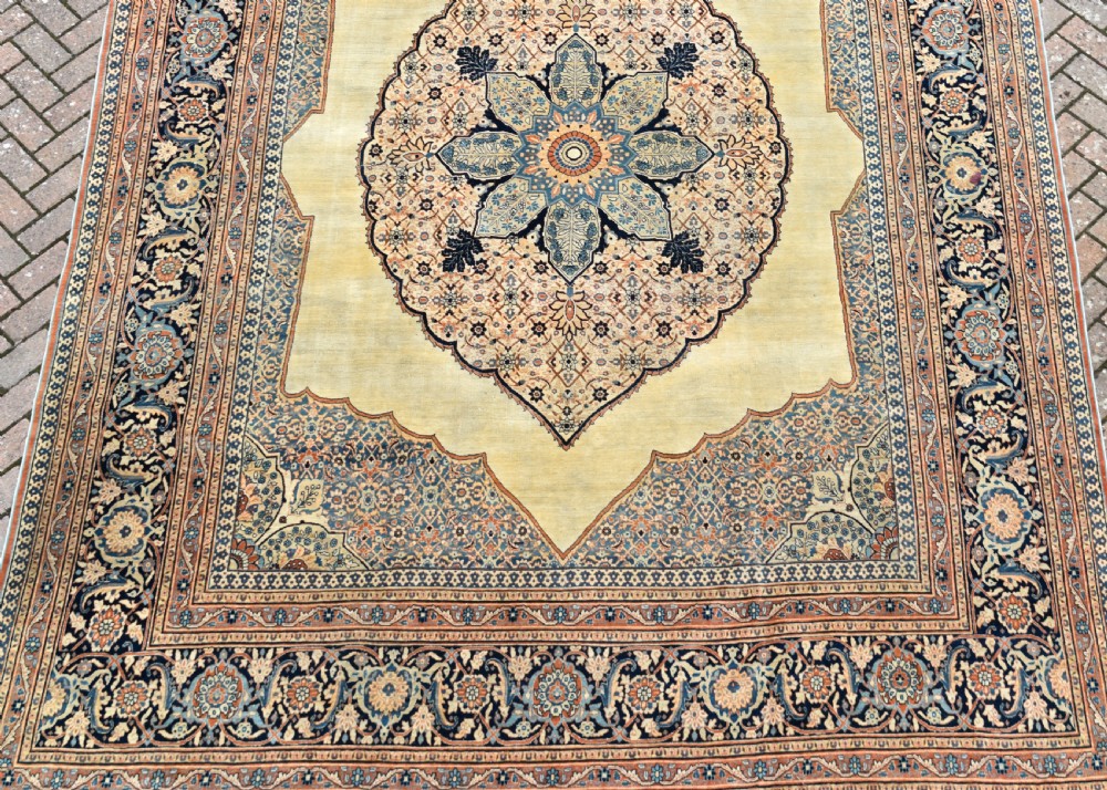 A large hand-knotted antique Persian Hajji Jalili carpet featuring a central star-shaped medallion on a cream field surrounded by dark blue floral borders. View II