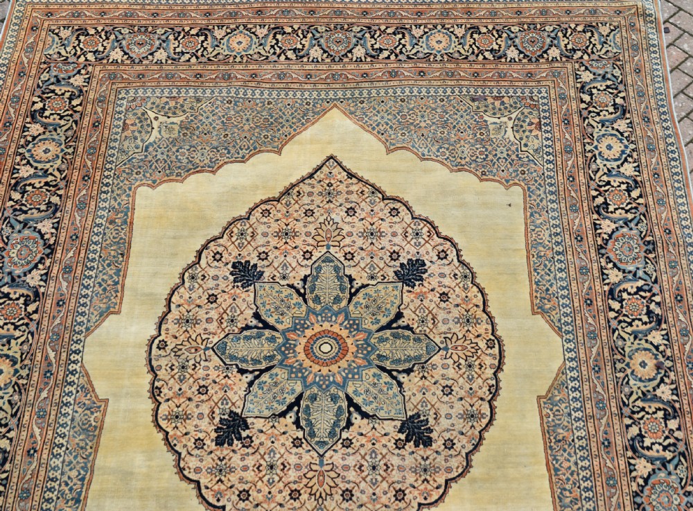 A large hand-knotted antique Persian Hajji Jalili carpet featuring a central star-shaped medallion on a cream field surrounded by dark blue floral borders. View III
