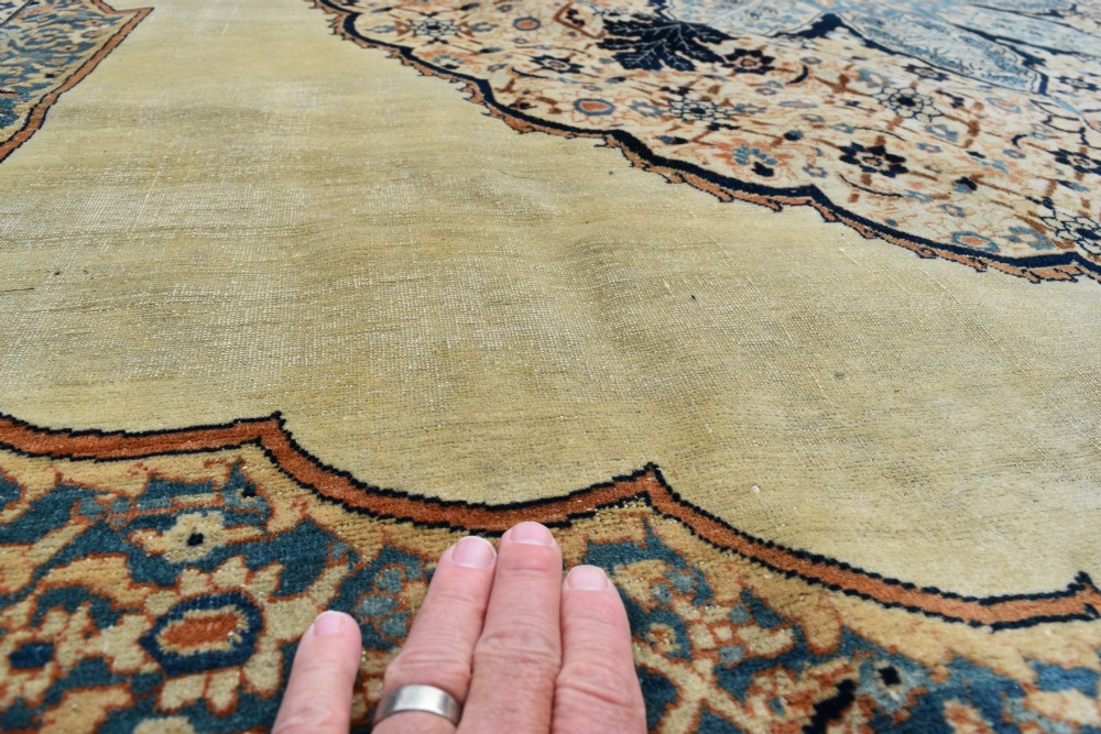 A large hand-knotted antique Persian Hajji Jalili carpet featuring a central star-shaped medallion on a cream field surrounded by dark blue floral borders. View VIII