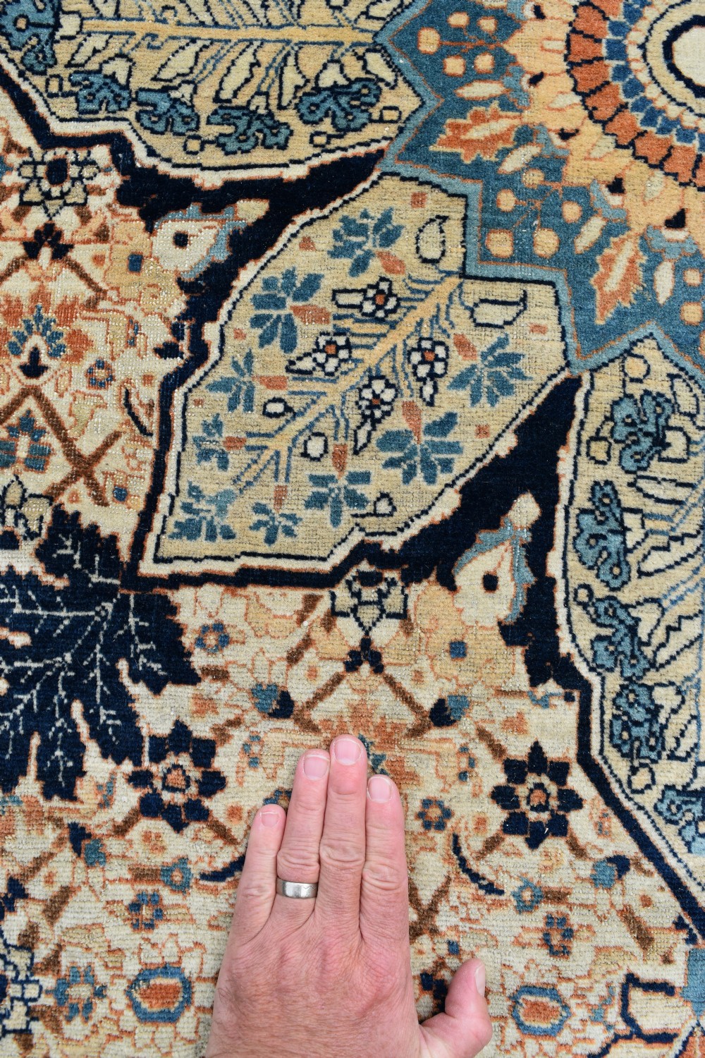 A large hand-knotted antique Persian Hajji Jalili carpet featuring a central star-shaped medallion on a cream field surrounded by dark blue floral borders. View IX