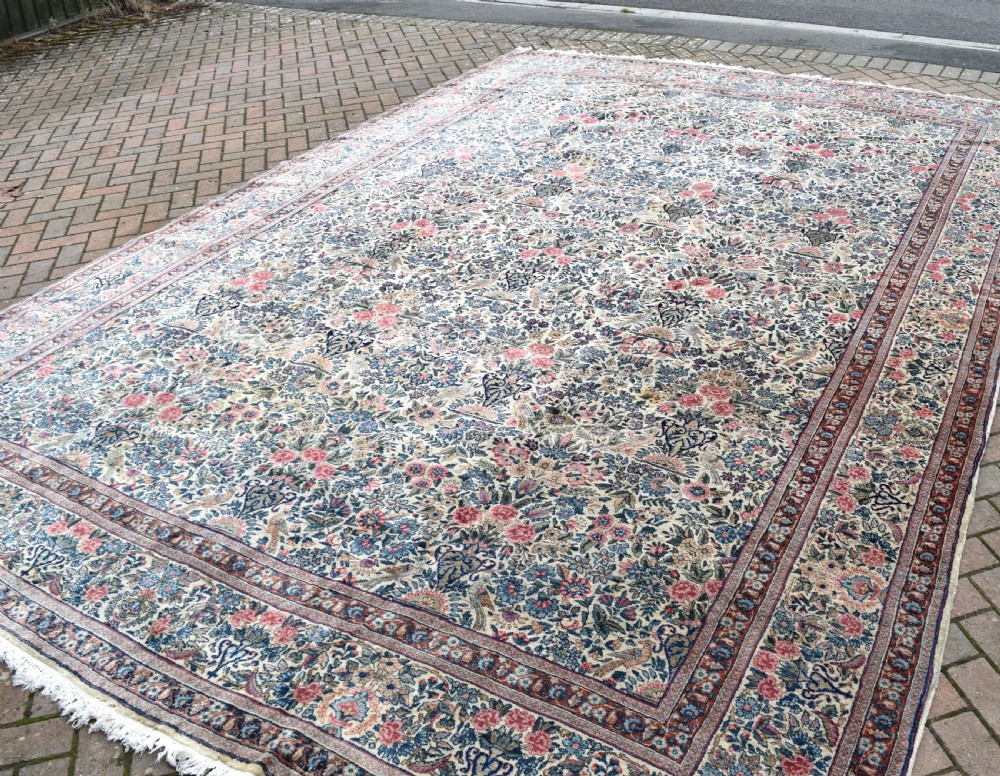A large hand-knotted Persian Kirman room-size carpet featuring an intricate floral and vase pattern in cream, rose pink, and slate blue. View IV