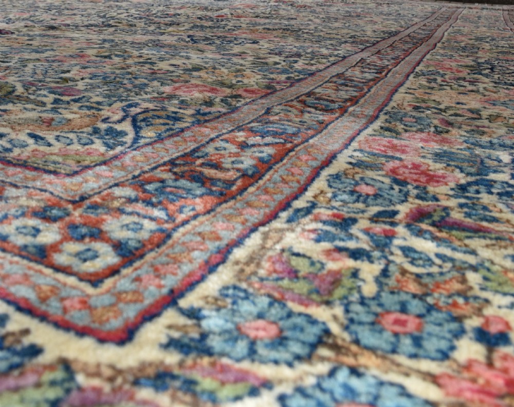 A large hand-knotted Persian Kirman room-size carpet featuring an intricate floral and vase pattern in cream, rose pink, and slate blue. View VII