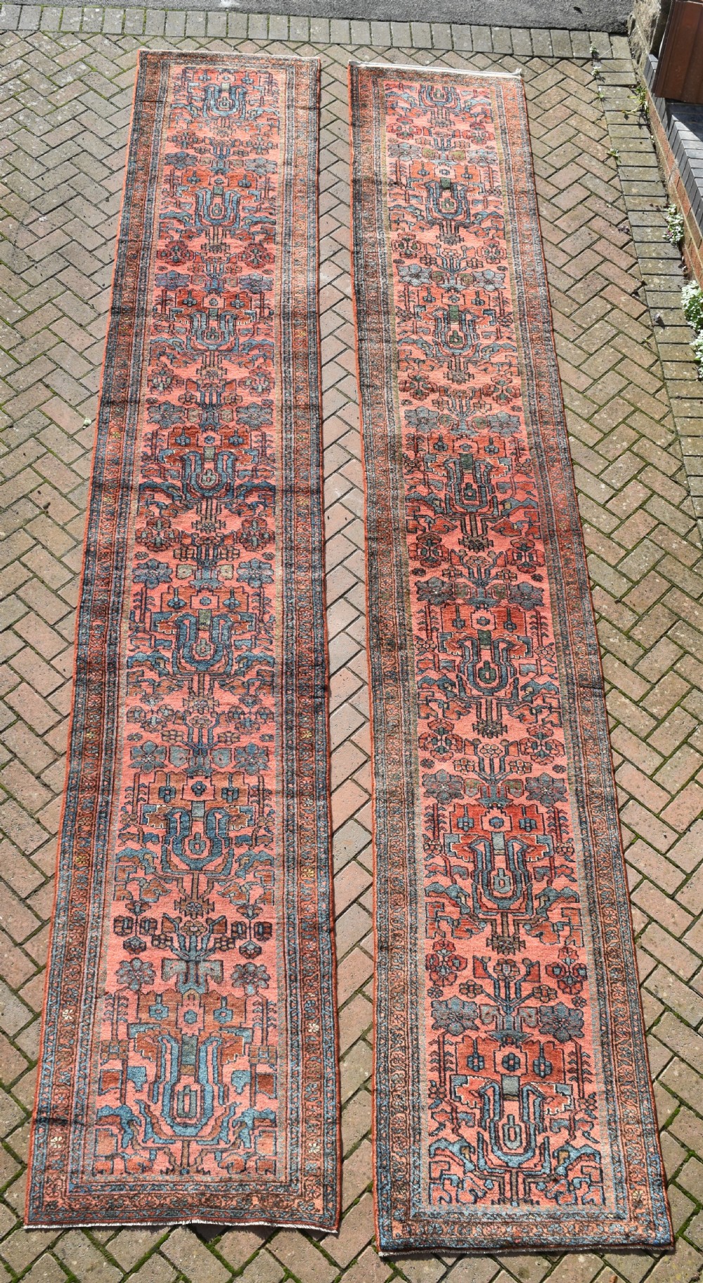 A pair of exceptionally long, narrow antique Persian Hamadan runners featuring intricate geometric and stylized floral motifs in blue and ivory on a terracotta wool ground.