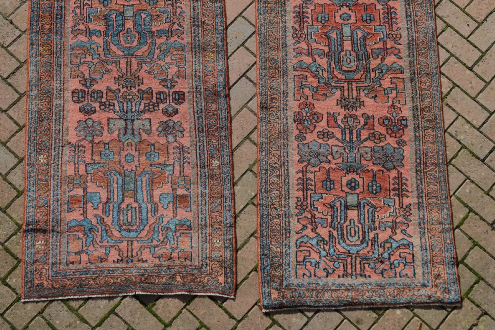 A pair of exceptionally long, narrow antique Persian Hamadan runners featuring intricate geometric and stylized floral motifs in blue and ivory on a terracotta wool ground. View II