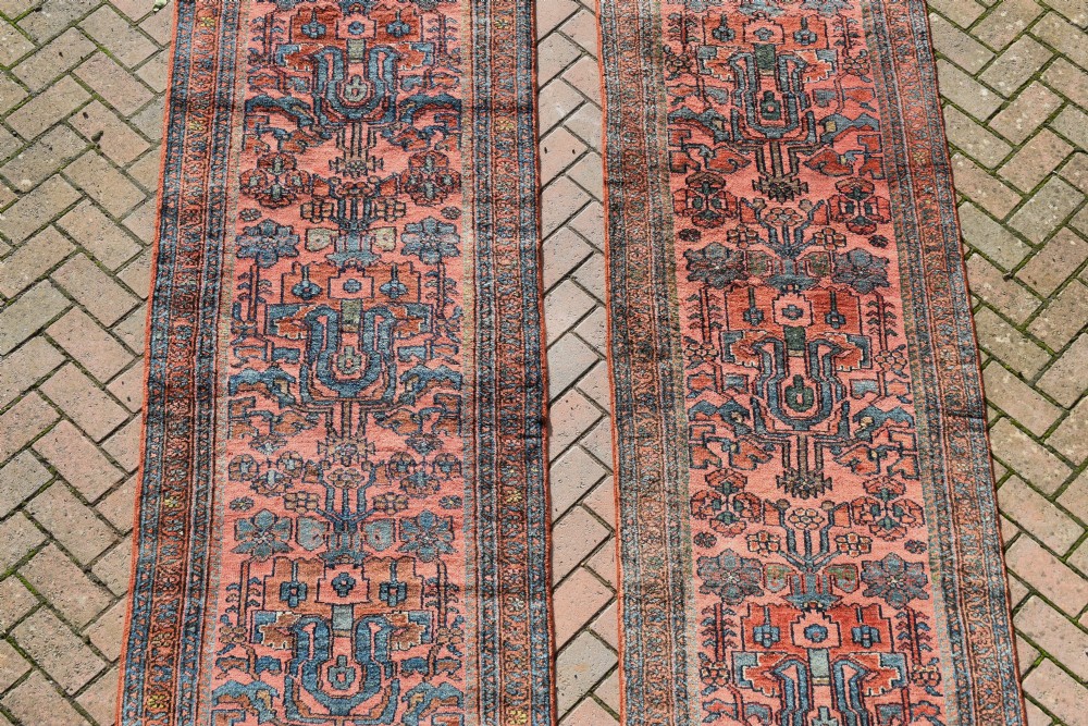 A pair of exceptionally long, narrow antique Persian Hamadan runners featuring intricate geometric and stylized floral motifs in blue and ivory on a terracotta wool ground. View III