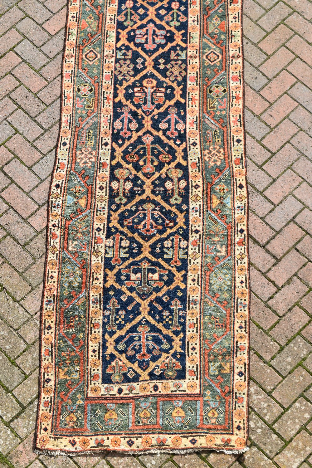 An extra long antique hand-knotted wool runner rug with a dark blue central panel of geometric diamond medallions and terracotta patterned borders. View II