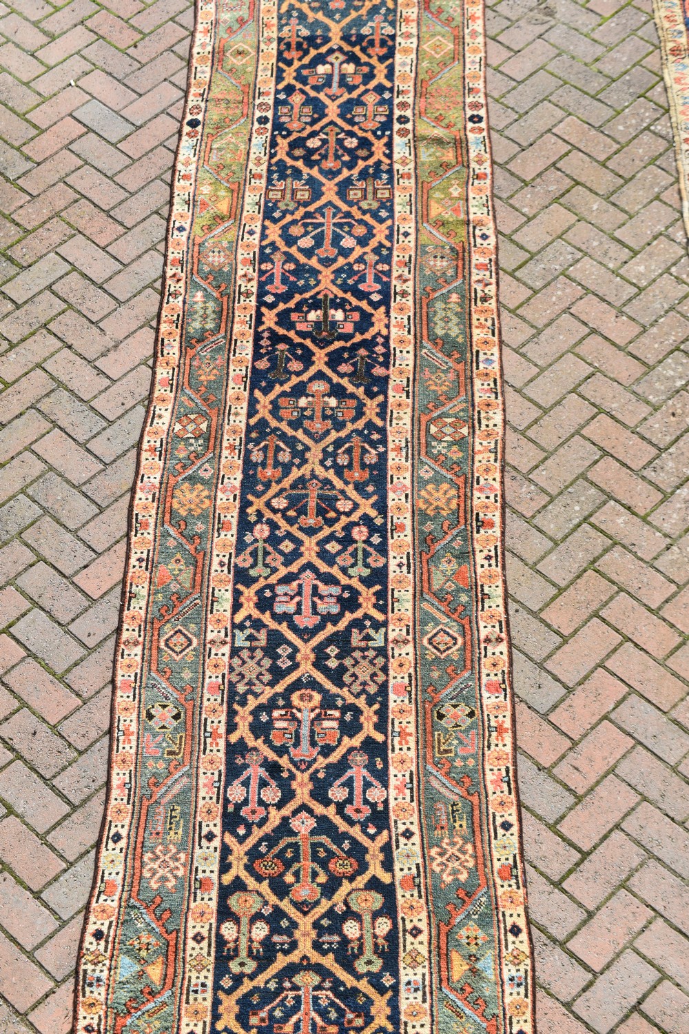 An extra long antique hand-knotted wool runner rug with a dark blue central panel of geometric diamond medallions and terracotta patterned borders. View III