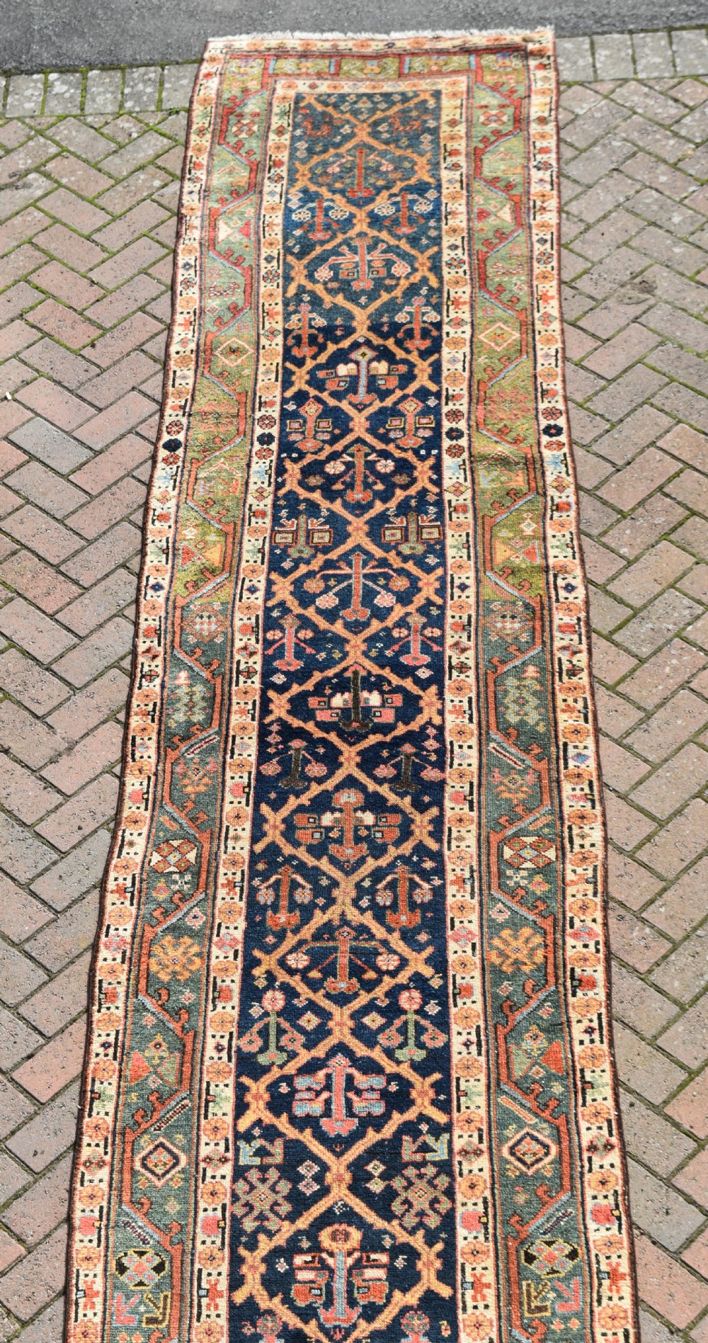 An extra long antique hand-knotted wool runner rug with a dark blue central panel of geometric diamond medallions and terracotta patterned borders. View IV