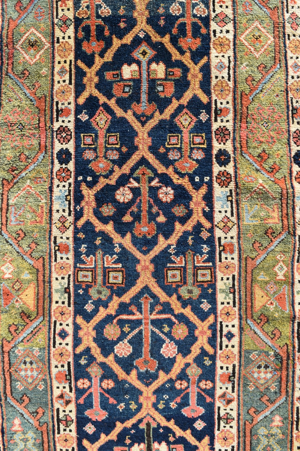 An extra long antique hand-knotted wool runner rug with a dark blue central panel of geometric diamond medallions and terracotta patterned borders. View V