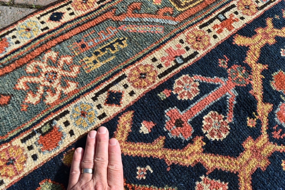 An extra long antique hand-knotted wool runner rug with a dark blue central panel of geometric diamond medallions and terracotta patterned borders. View VI