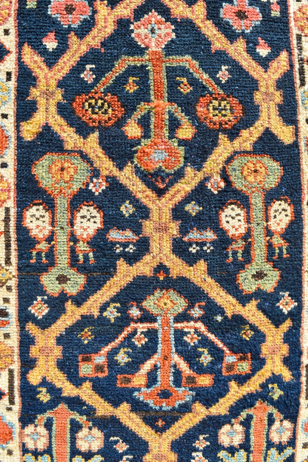 An extra long antique hand-knotted wool runner rug with a dark blue central panel of geometric diamond medallions and terracotta patterned borders. View VII